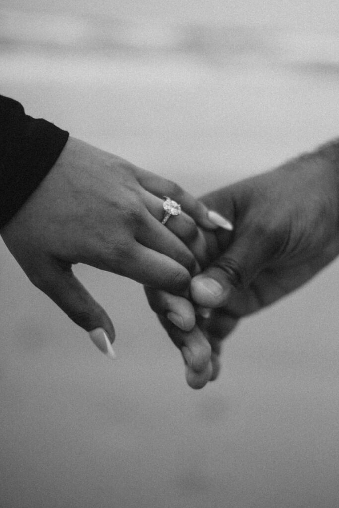 Couple holding hands with engagement ring